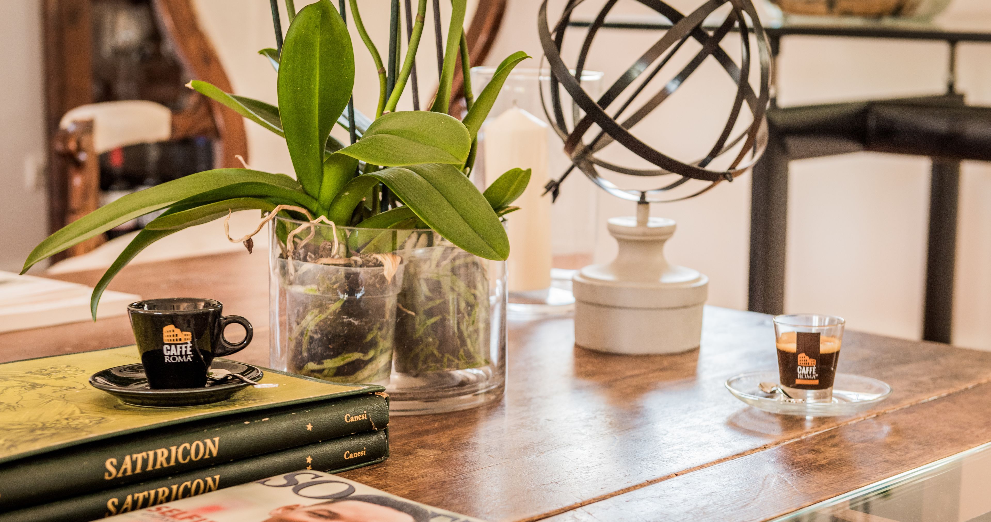 Una mesa con una taza de café, libros, una planta en maceta y un globo terráqueo.