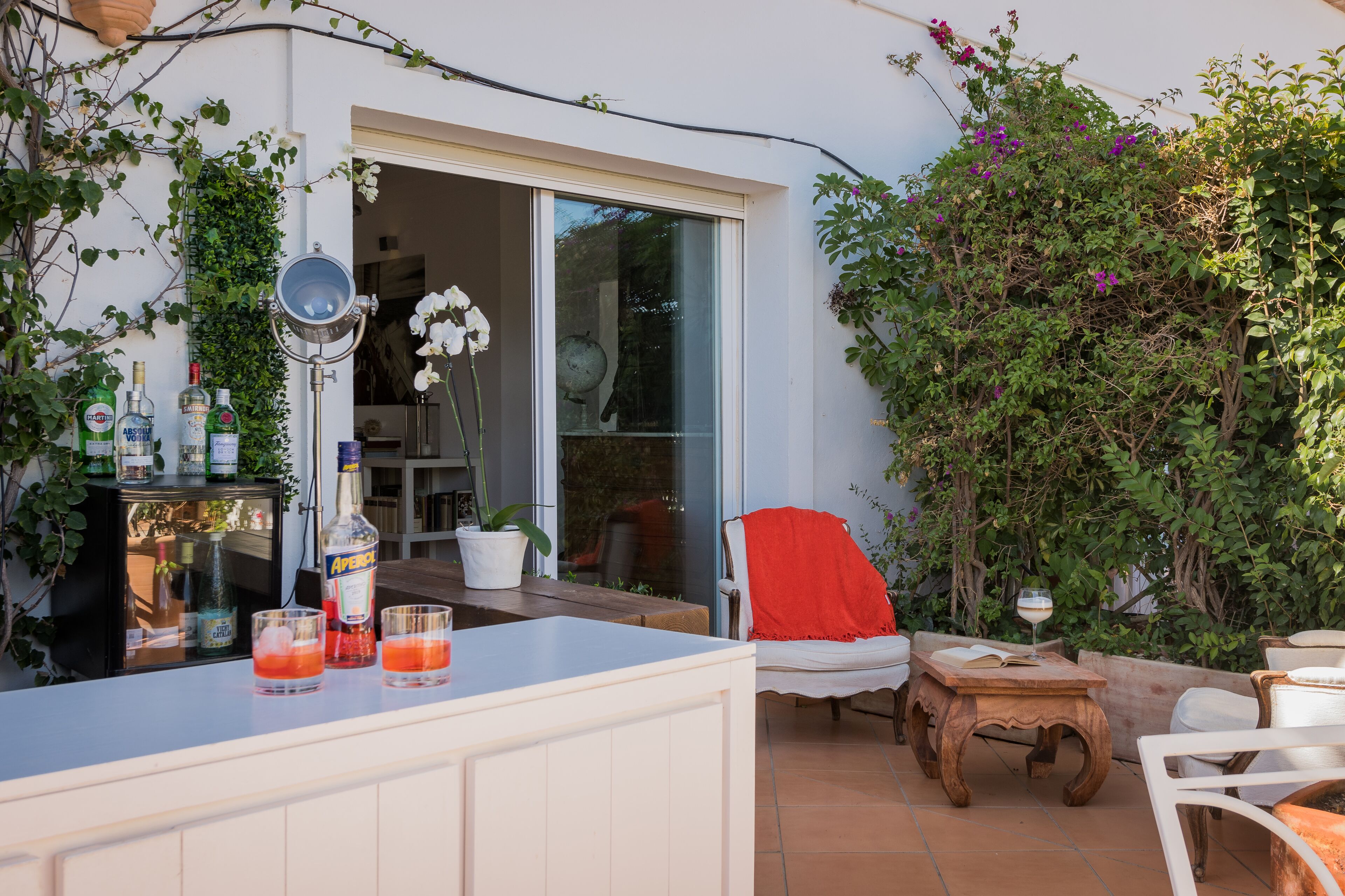 An outdoor patio with a bar area, a chair, a table, and a potted plant.