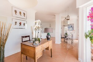 Een kamer met een houten bureau, stoelen, een lamp en wanddecoratie.