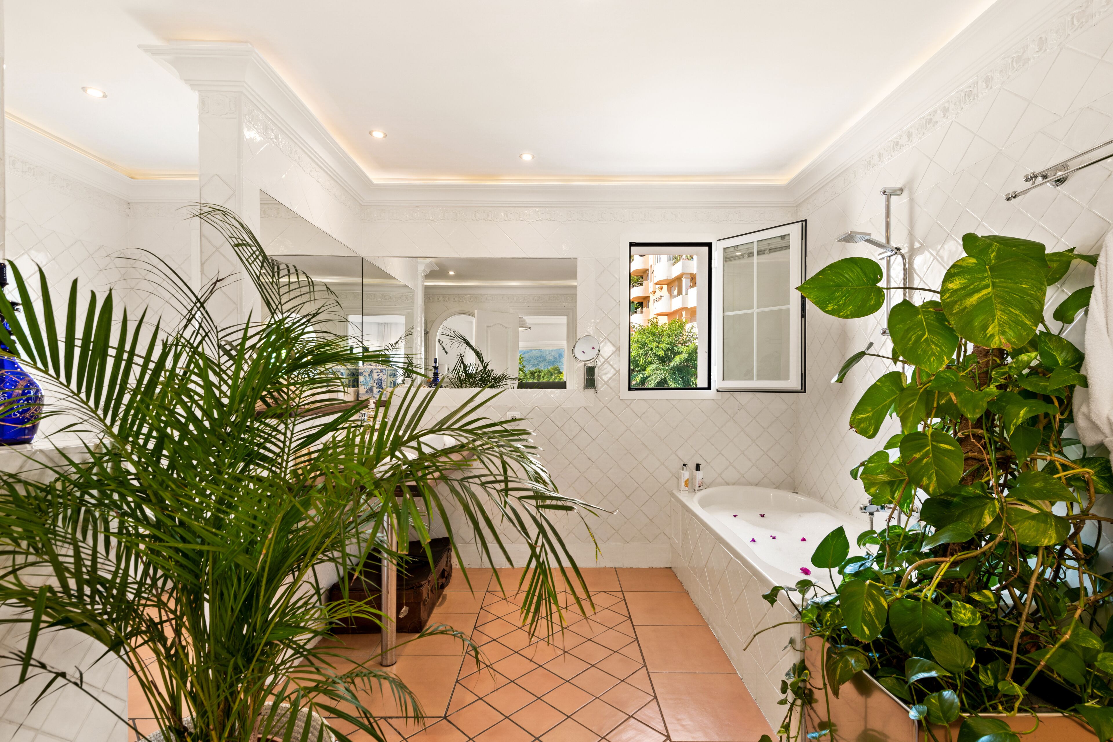 A spacious bathroom with a large bathtub, a shower, and a view of a residential area.