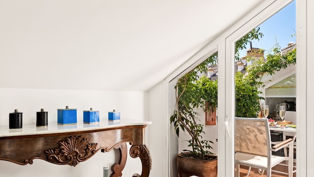A bathroom with a large bathtub, a wooden shelf with containers, and a potted plant.