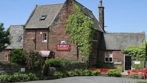 A traditional stone building with a sign indicating a pub.