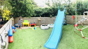 A children's play area with a slide, climbing net, and inflatable toys.