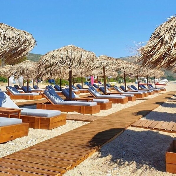 Un resort frente al mar con sillones de madera y sombrillas de paja.
