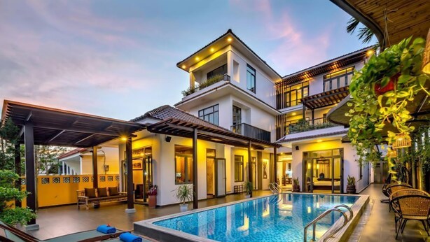 Un hotel moderno con piscina, mobiliario exterior y un patio cubierto.