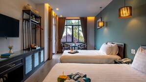 Habitación de hotel con dos camas, un escritorio, un televisor y vistas a palmeras a través de la ventana.