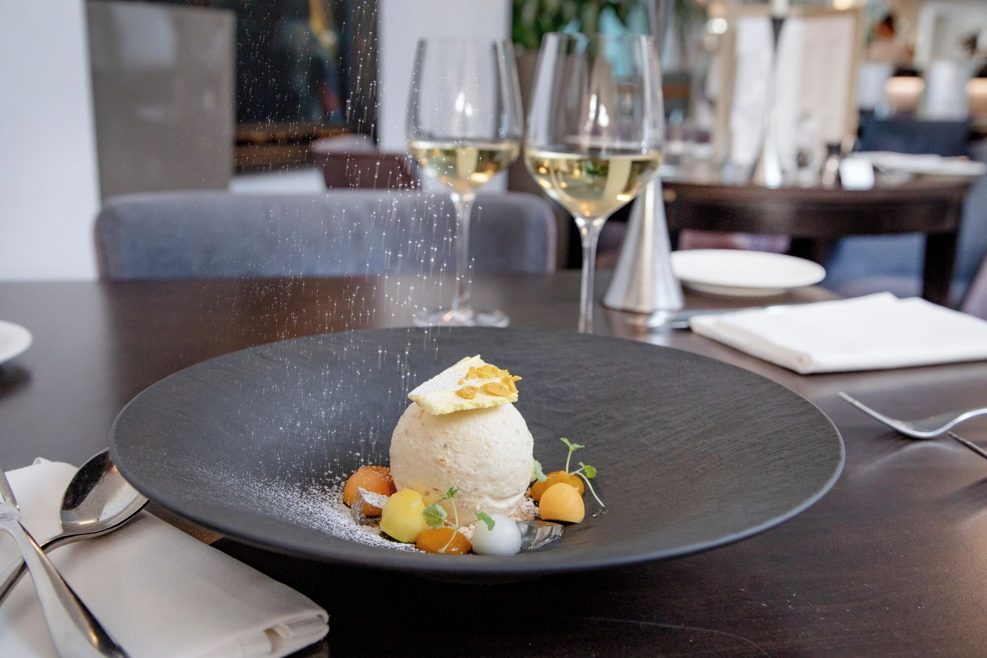 A dessert on a black plate with a spoon and napkin beside it.