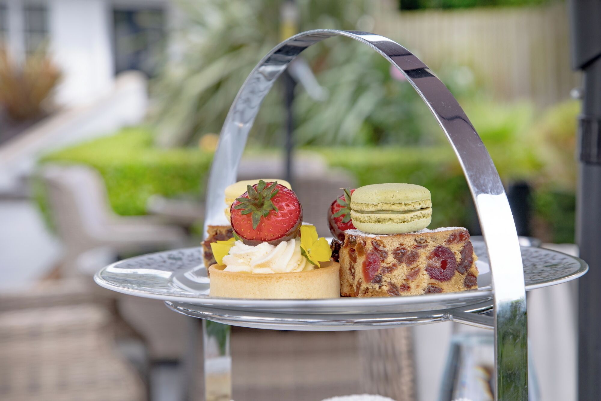 Un soporte de tres niveles para postres con diversos pasteles y una estructura de metal en arco.