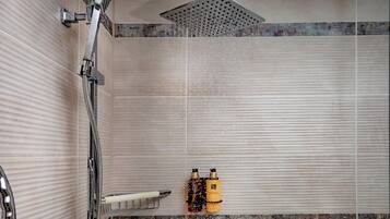 A shower area with a rain showerhead, a towel rack, and two bottles of shampoo.