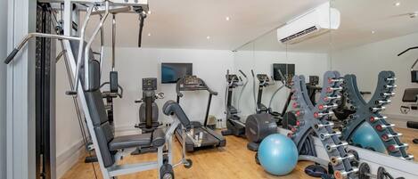 A gym with exercise equipment, a mirror, and a television.