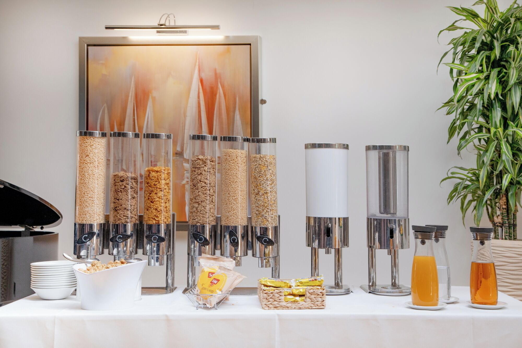 A buffet setup with various food containers, a coffee machine, and a plant.