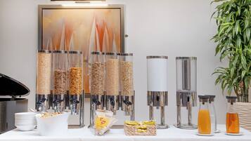 A buffet setup with various food containers, a coffee machine, and a plant.