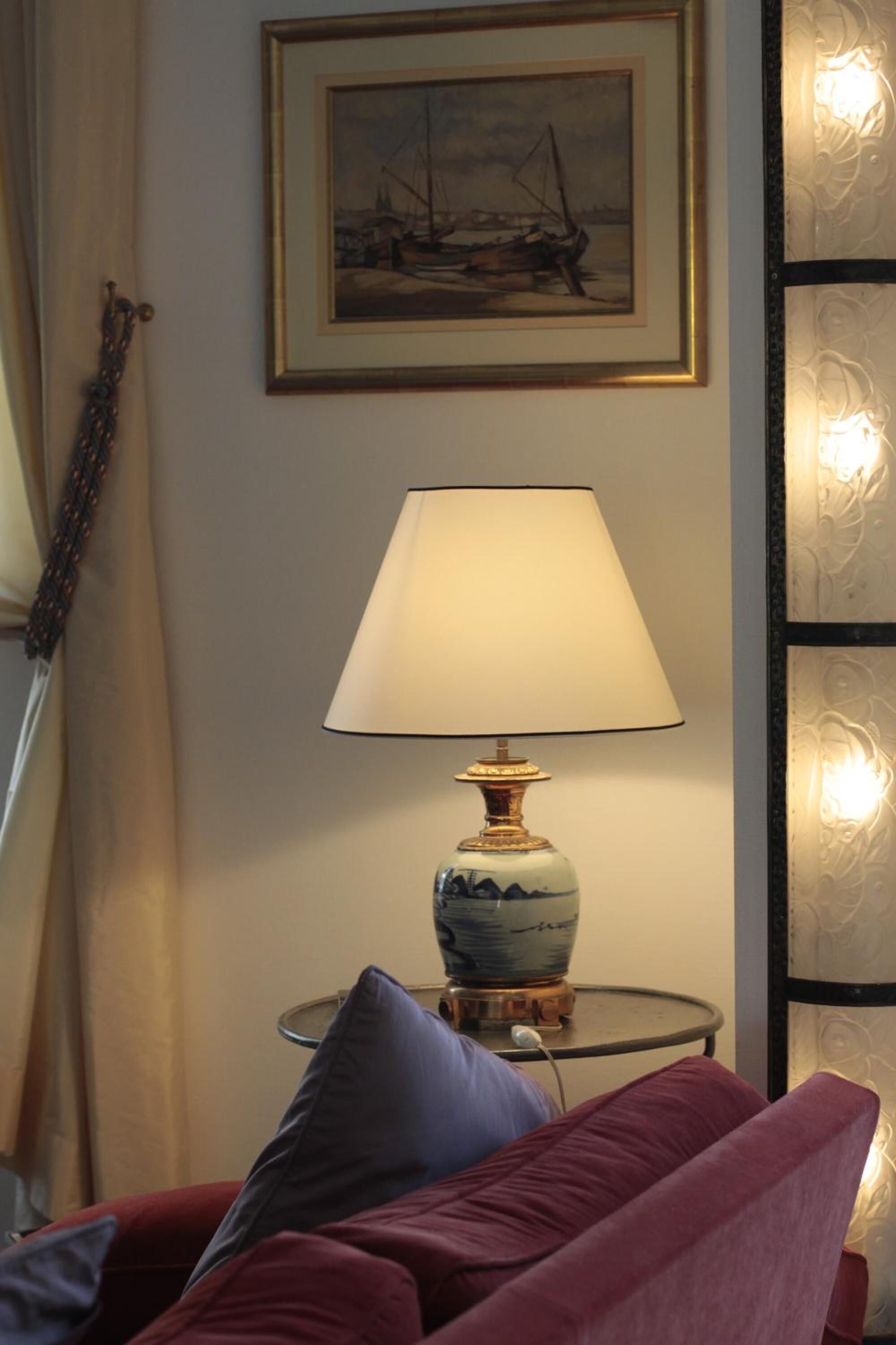 Une pièce avec un canapé rouge, une table avec une lampe, un tableau encadré au mur et un panneau décoratif.