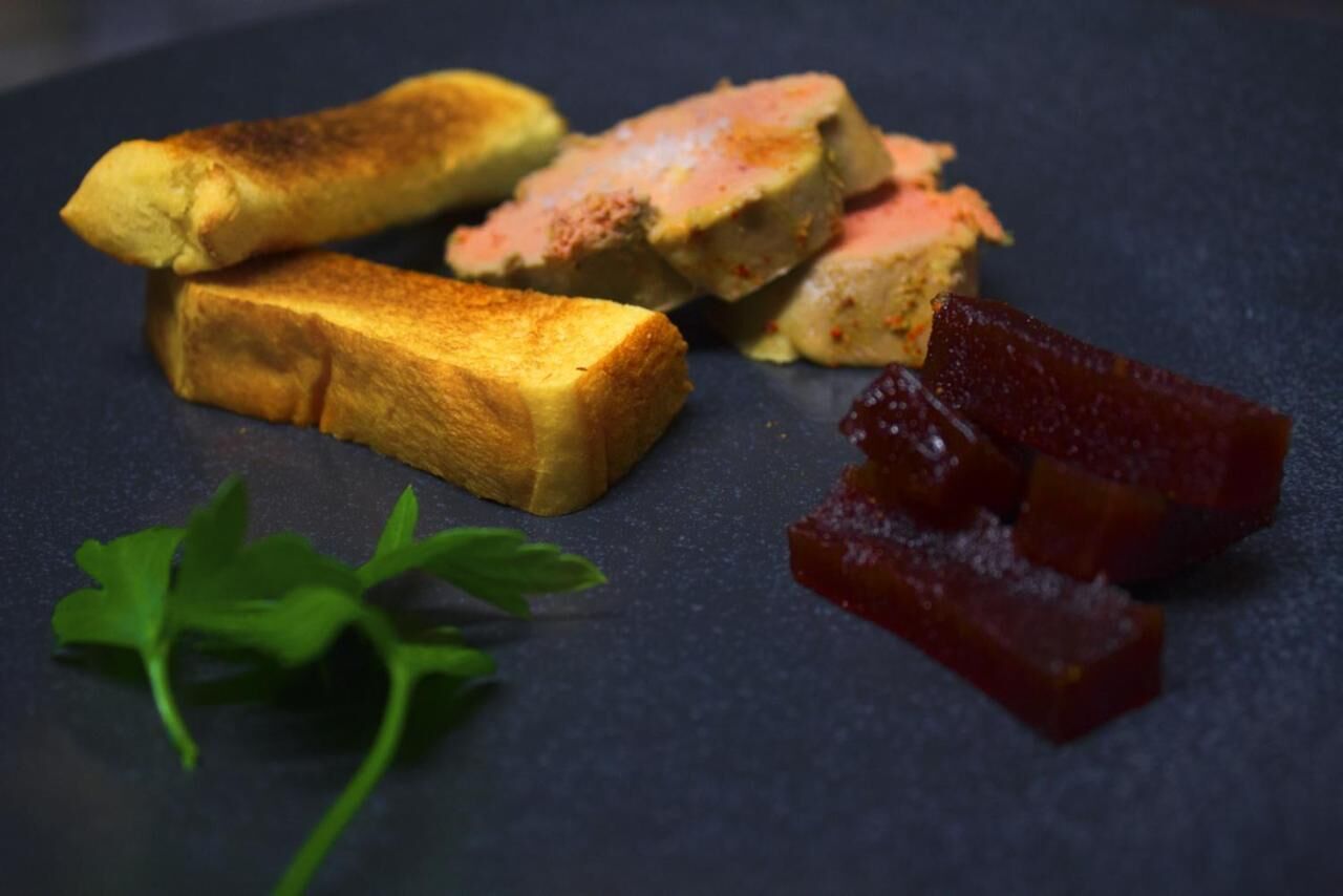 A plate with toasted bread, a slice of cake, and some red fruit pieces.