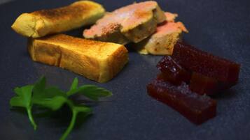 A plate with toasted bread, a slice of cake, and some red fruit pieces.