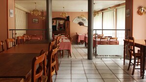 A dining area with wooden tables and chairs, a fan, and hanging lights. - Hôtel Restaurant de l'Abbaye (Sauxillanges)