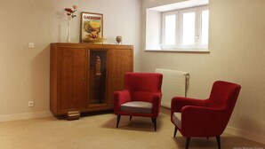 A room with a wooden cabinet, two red armchairs, a radiator, and a window. - Hôtel Restaurant de l'Abbaye (Sauxillanges)