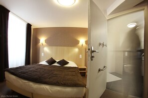 A hotel room with a bed, bedside lamps, a shower, and a view of the outside. - Hôtel Restaurant de l'Abbaye (Sauxillanges)