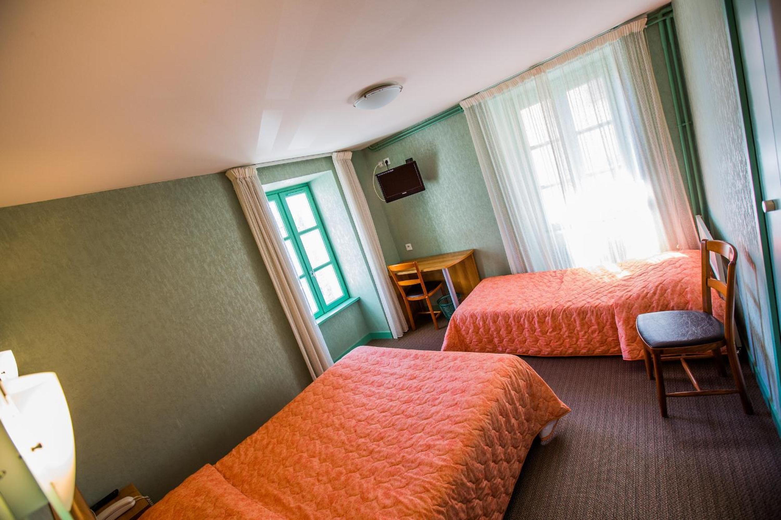 A room with two beds, a desk, and a chair.