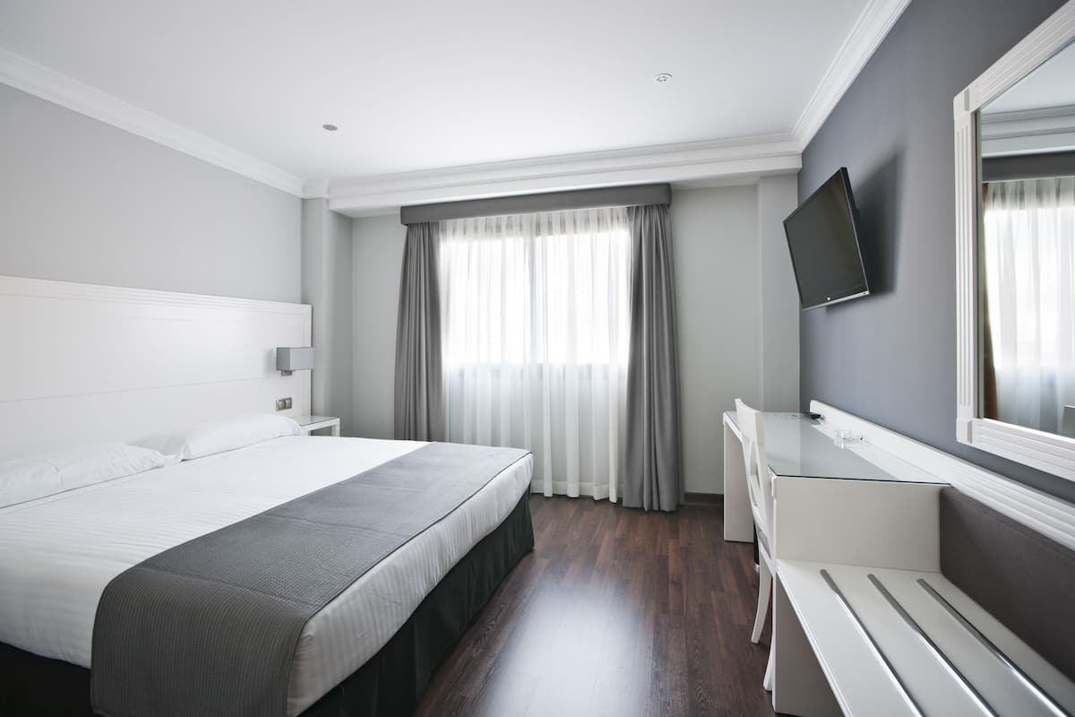 Una camera d'albergo moderna con un letto grande, una scrivania e una televisione.