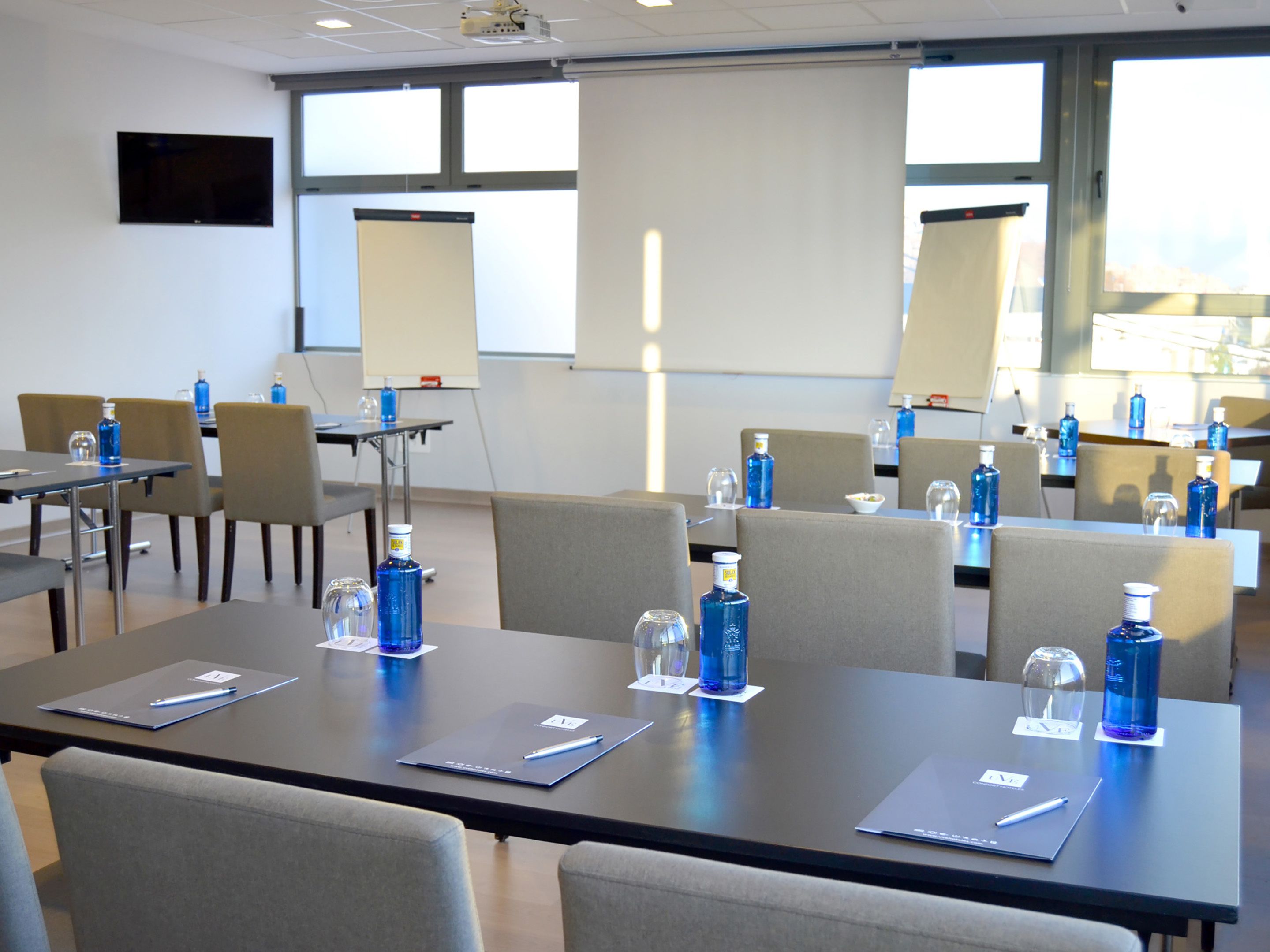 A conference room with tables, chairs, and presentation screens.