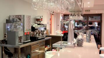 Interior de una cafetería moderna con una máquina de café, vasos y mostrador.