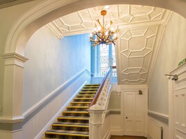 A grand staircase with a white balustrade, a chandelier, and a blue wall.