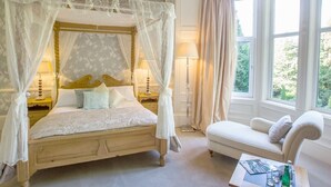 A bedroom with a four-poster bed, a bedside table, a nightstand, a window with curtains, and a sofa. - Balcary House Hotel (Hawick)