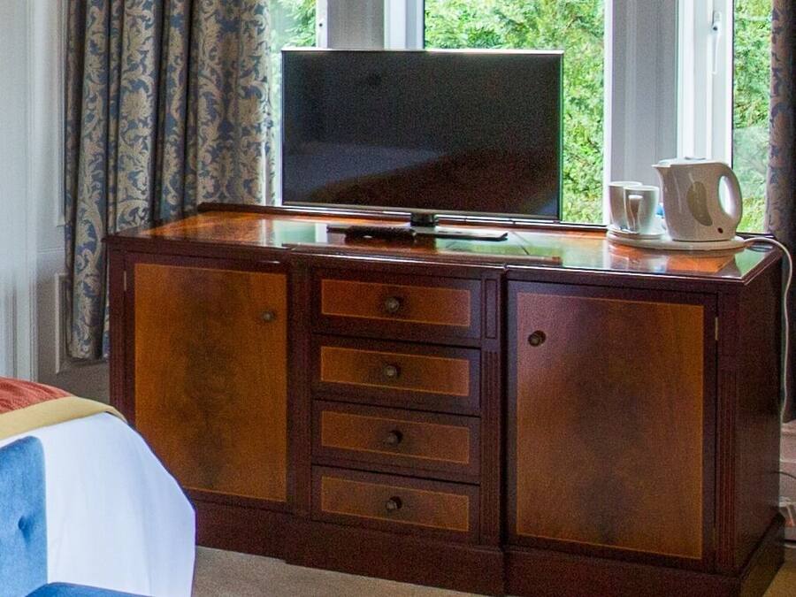Un mueble de madera con un televisor, cajones y una cafetera encima.