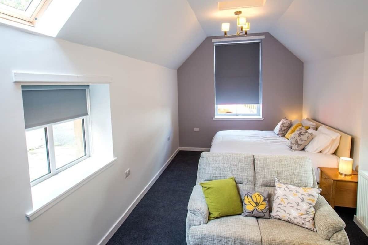 A bedroom with a bed, a sofa, a window, and a skylight.