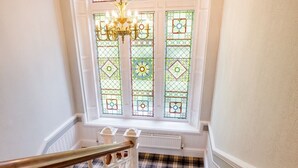 A staircase with a checkered floor, a chandelier, and stained glass windows. - Balcary House Hotel (Hawick)