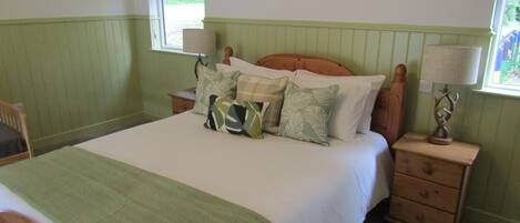 A bedroom with a bed, pillows, a nightstand, a lamp, and a framed deer head on the wall.