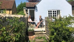 A small white cottage with a stone wall and a wooden door. - Clare Cottage (Sherborne)