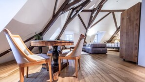 Una habitación tipo loft con piso de madera, una mesa redonda de madera y dos sillones tapizados.