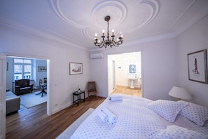 A hotel room with a large bed, a chandelier, a desk, and a view of the bathroom. - Ulner Kapelle (Weinheim)
