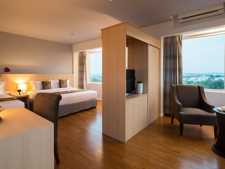 A hotel room with a bed, a desk, a chair, a TV, and a large window offering a city view.