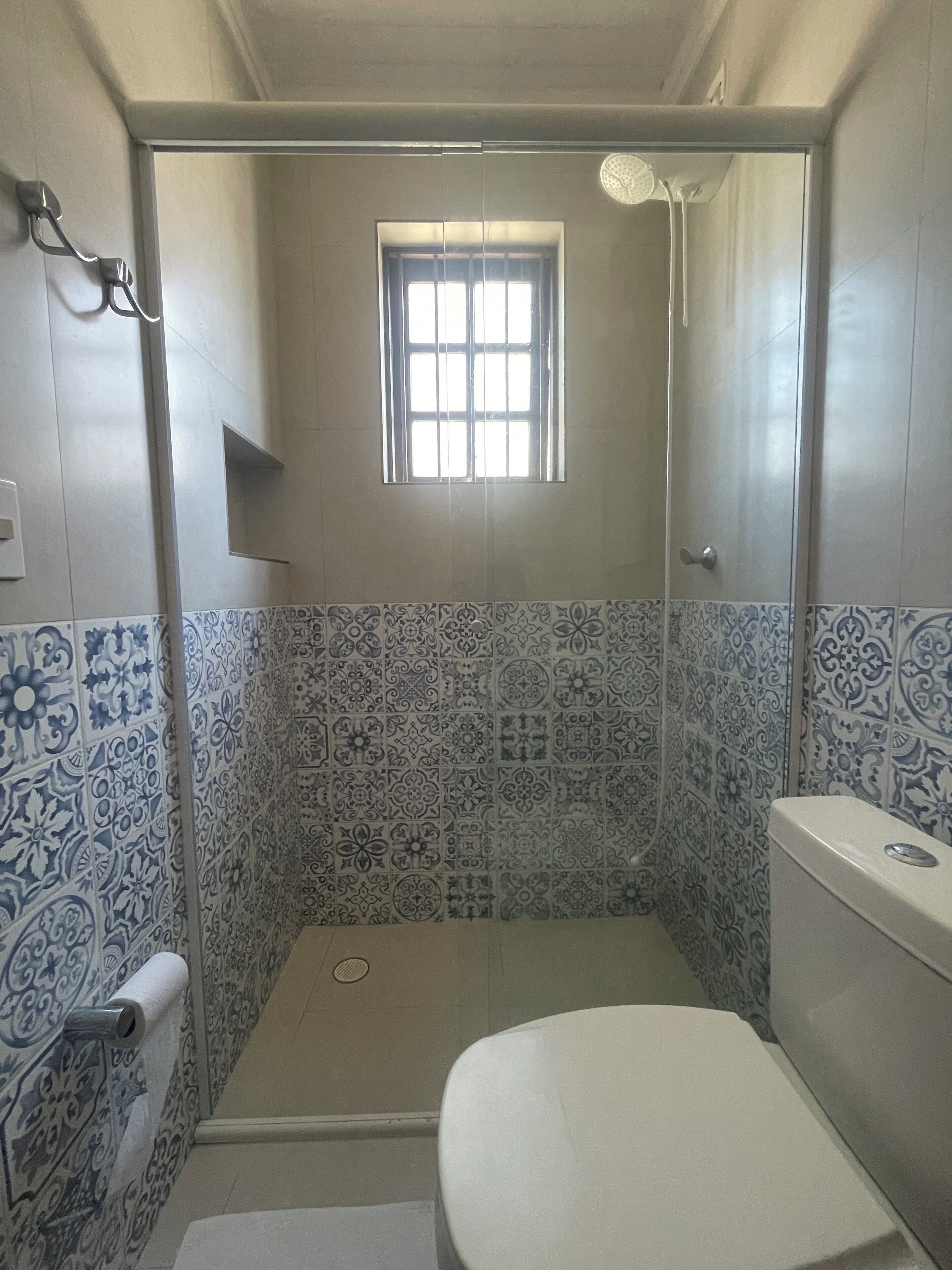 Un baño pequeño con ducha, inodoro y ventana.