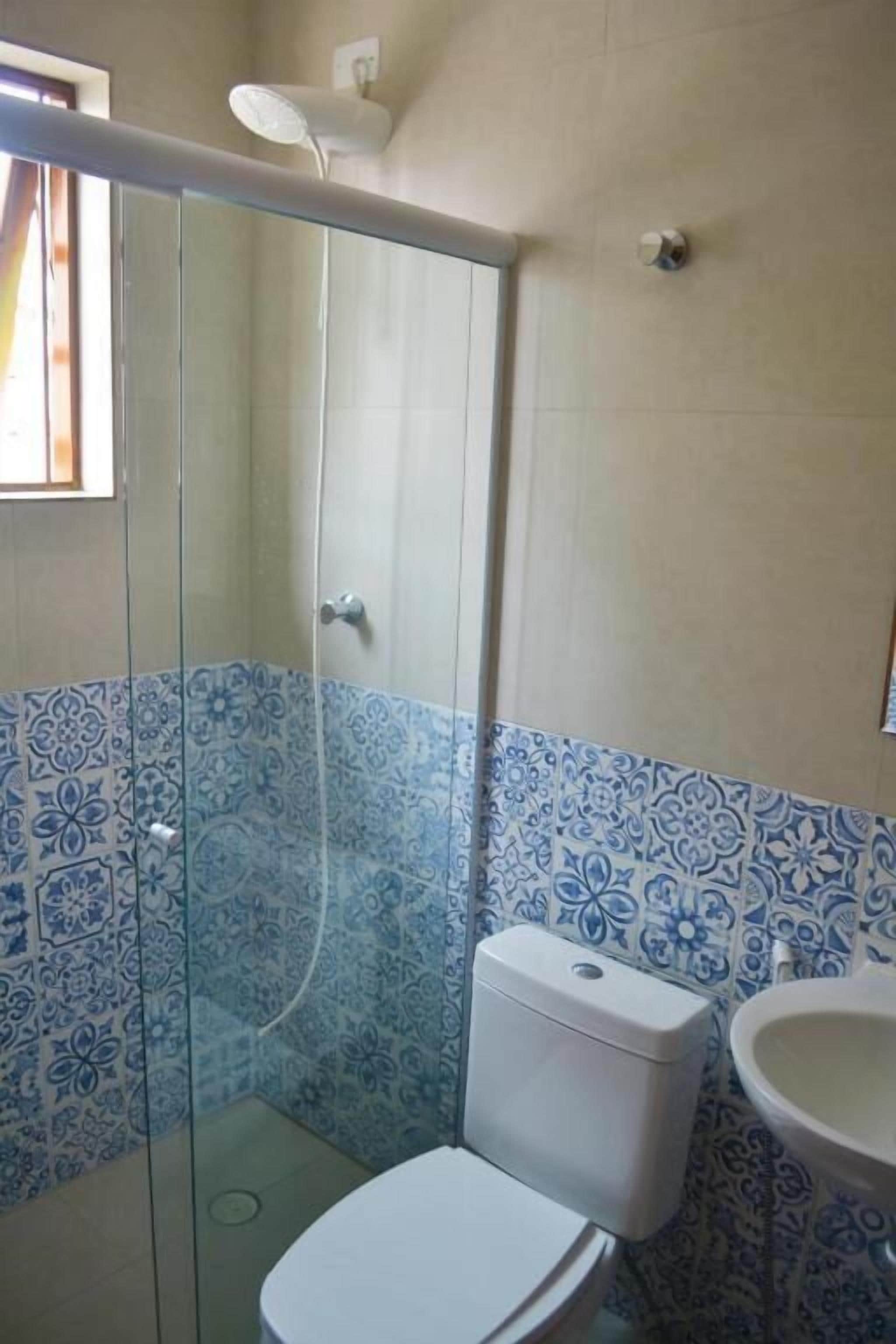 Un baño con cabina de ducha de vidrio, inodoro y lavamanos.