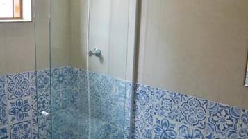 Un baño con cabina de ducha de vidrio, inodoro y lavamanos.