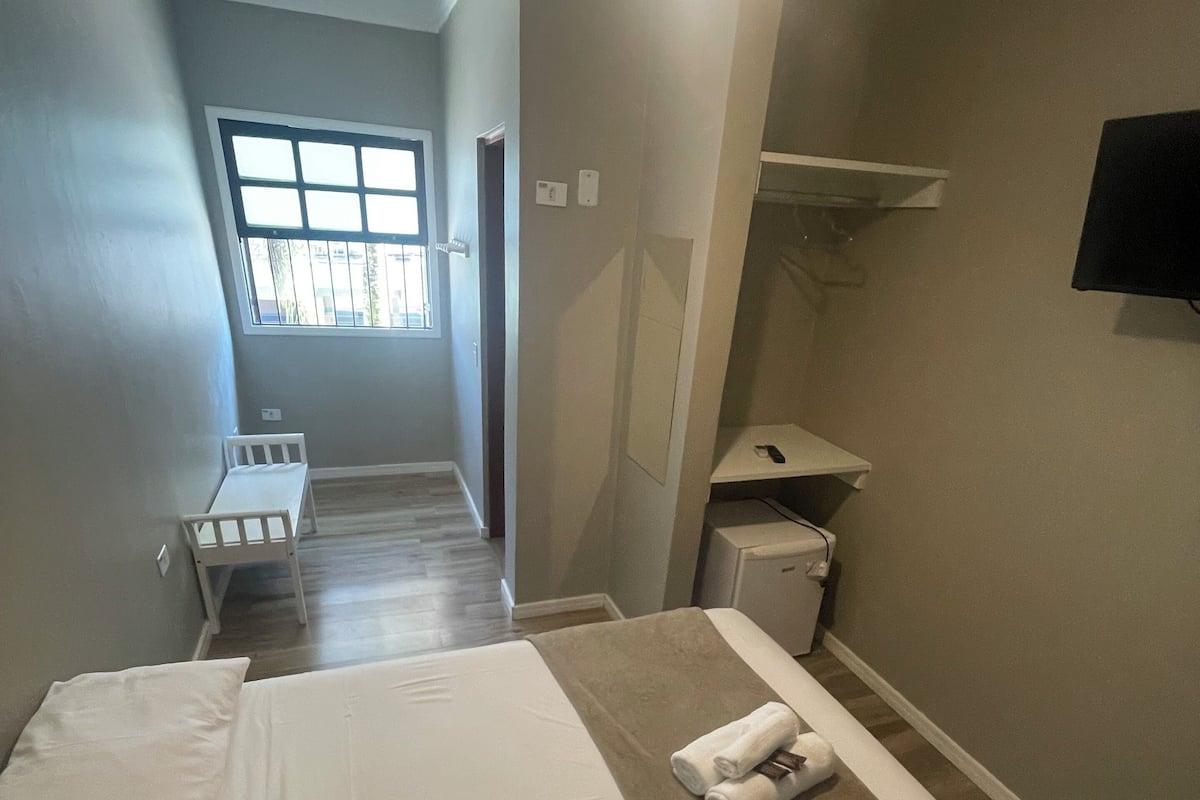 A hotel room with two beds, a window, a TV, and a small desk.