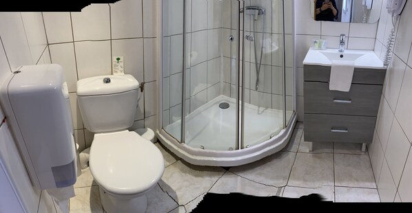 Un baño con inodoro, ducha de vidrio y lavamanos con toalla.