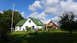 A two-story house with a green roof and white walls, a flagpole, and a well-maintained lawn. - Lilla Trulla Gårdshotell - Feels like home (Klippan)