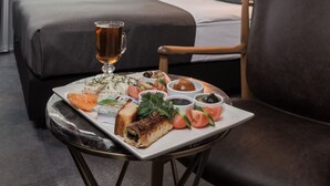 A hotel room with a bed, a dining table with food, a chair, and artwork on the wall. - Hotel Cinnah (Ankara)