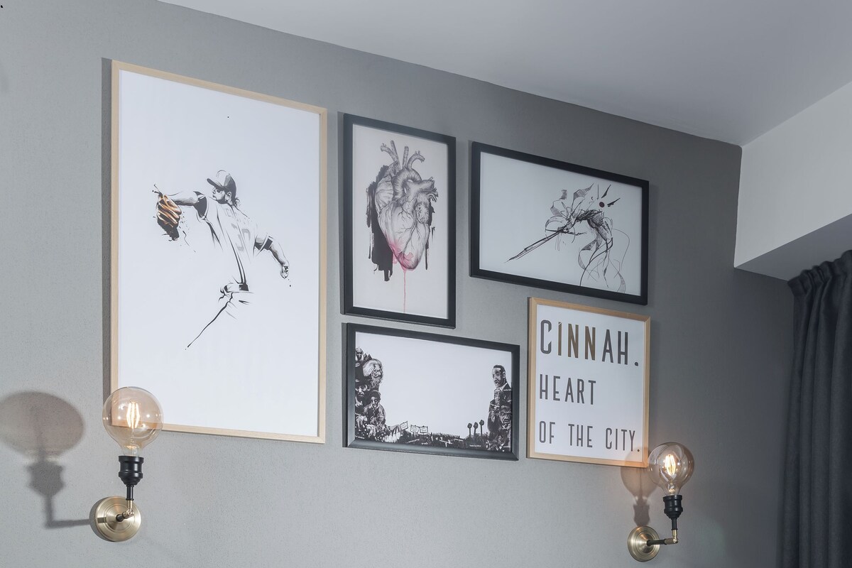 A modern hotel room with a bed, laptop, and artwork on the wall.