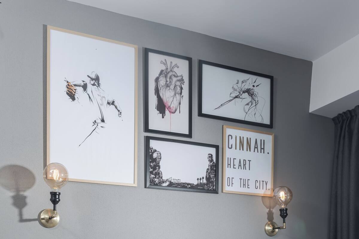 A modern hotel room with a bed, laptop, and artwork on the wall.
