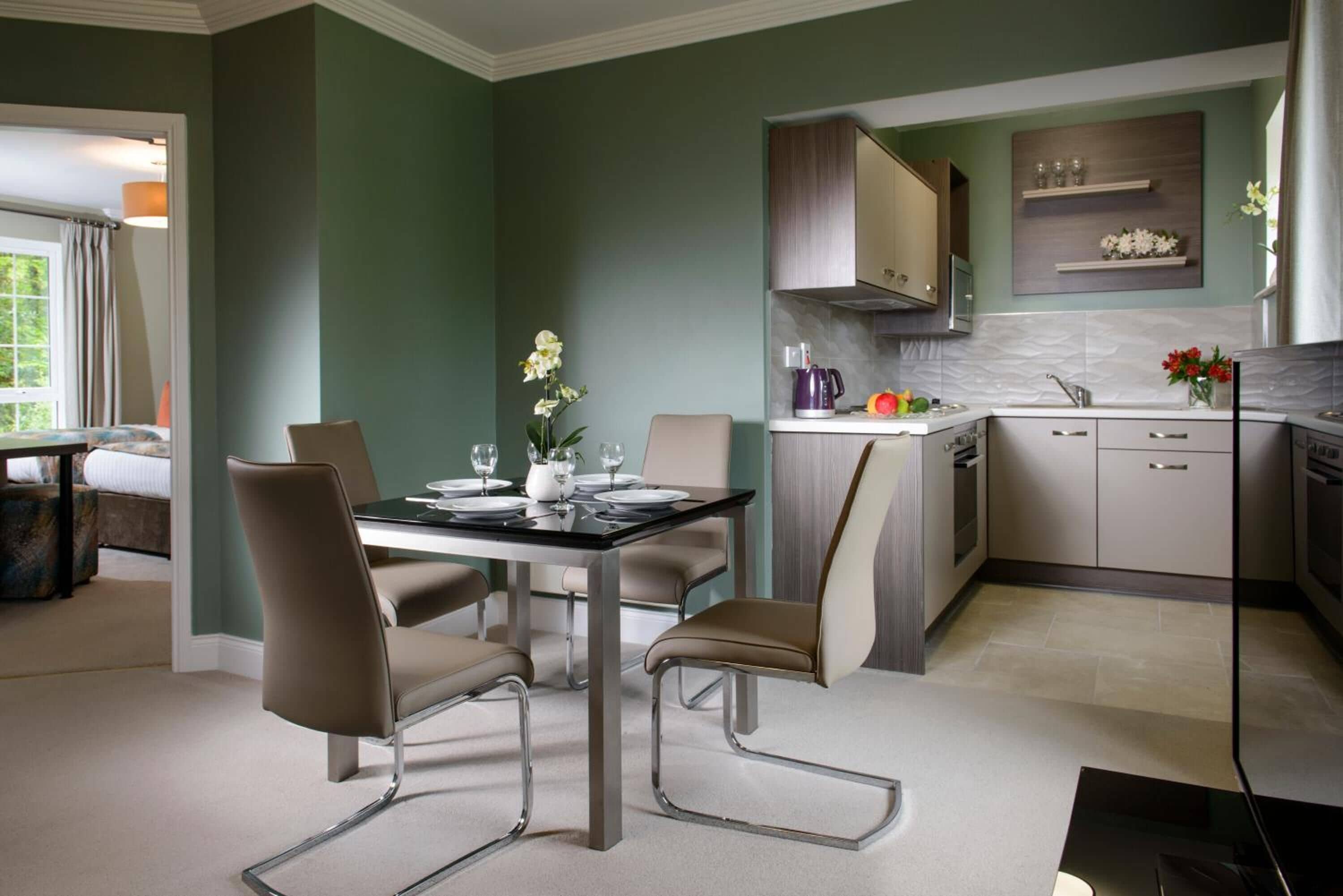 Una cocina moderna con comedor, que incluye una mesa preparada para cuatro personas, sillas y una cafetera.