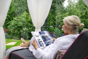 Una persona leyendo una revista en una habitación con vistas a un jardín.