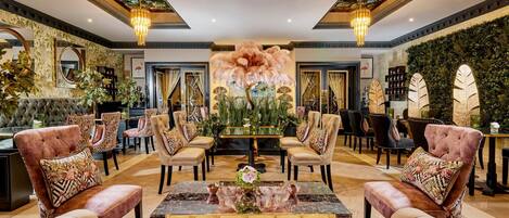 Eine luxuriöse Lobby mit bequemen Sitzmöglichkeiten, einem zentralen Tisch und dekorativen Wandbildern.