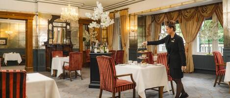 Une salle à manger élégante, avec des chaises à rayures, des tables blanches et des lustres.