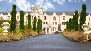 Un grand bâtiment imposant, qui ressemble à un château, avec une tour centrale, des fenêtres disposées de manière symétrique et une allée pavée menant à l’entrée.
